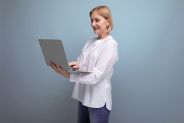 middle-aged woman with blond hair solves work tasks using a laptop