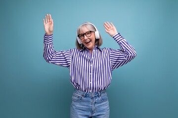 Naklejka premium happy middle aged woman with gray hair with headphones on bright studio background