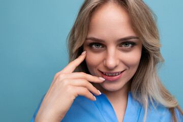 photo of shy cute casual young woman with smiling eyes on bright blue background