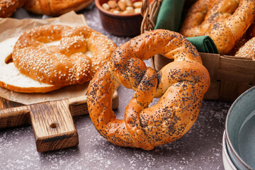 Wooden board with tasty pretzels on grunge background, closeup