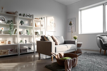 Interior of light living room with sofa, shelving units and artificial plants