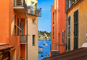 Old terracotta houses and the Mediterranean Sea in Villefranche sur Mer, France, - obrazy, fototapety, plakaty