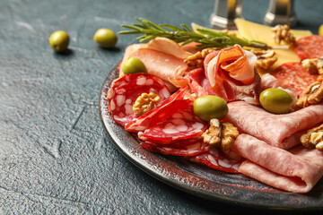Plate with assortment of tasty deli meats on black background, closeup
