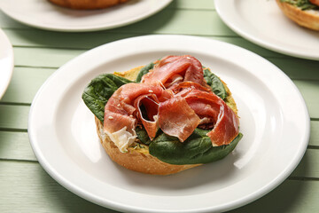 Tasty jamon bruschetta with spinach on green wooden background