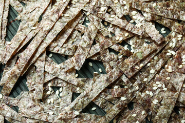 Bamboo mat with cut nori sheets and sesame seeds, closeup