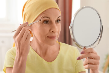 Mature woman after chemotherapy doing makeup in bedroom, closeup