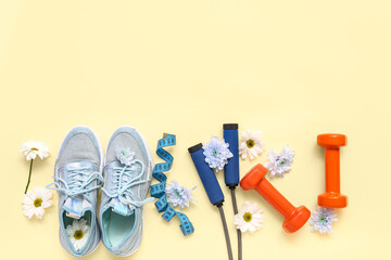Sneakers with spring flowers, sports equipment and tape measure on beige background