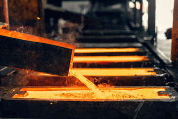 red-hot brass melt pours into the mold in a foundry