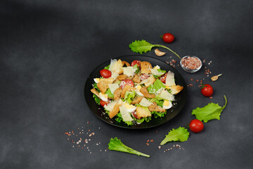 Caesar Salad in a black plate on a Black Background