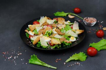 Caesar Salad in a black plate on a Black Background