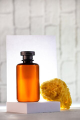 Cosmetic bottle on the podium and sea sponge at white background with back light.