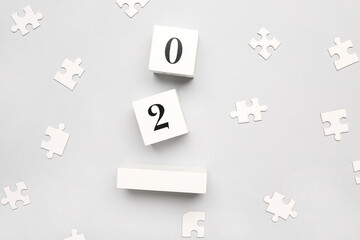 Date of World Autism Awareness Day with puzzle pieces on grey background