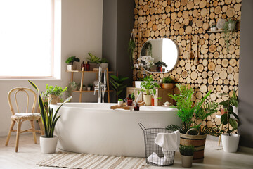 Interior of bathroom with green houseplants and bathtub