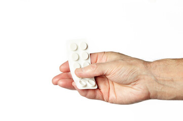 Men's hand holding white pills in common tablets shape isolated on white background. Hand with pills, closeup