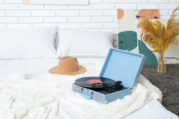 Record player with vinyl disk on bed in room