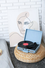 Record player with vinyl disk on pouf in bedroom
