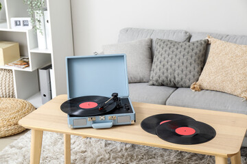 Record player with vinyl disks on table in living room
