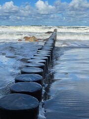 Fototapeta premium Wooden breakwaters on the Baltic Sea, stretching into the distance of the rolling waves.
