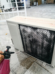A technician spraying a chemical substance on air conditioner compressor using water dispenser pump. Overhaul cleaning service . Chemical foam reacts to remove dirty dust and substances on coil. 