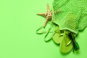 String bag with flip-flops, sunglasses and starfish on green background