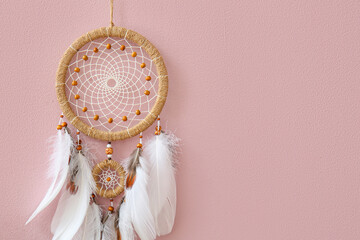 Dream catcher hanging on pink wall, closeup