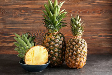 Fresh cut pineapples on black table near wooden wall