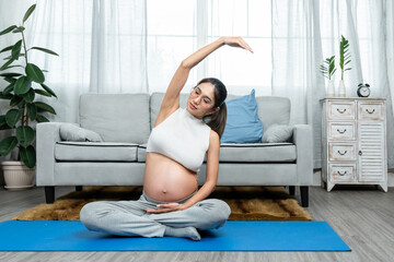 Pregnant Asian moms are ready to give birth. Raise your hands and rock your body. to stretch the body to relax, not stress make childbirth easy sitting on a yoga shirt in the living room