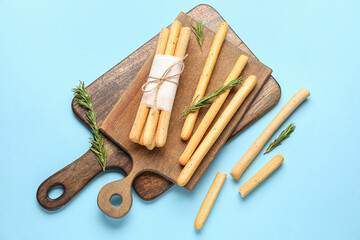 Wooden boards with bunch of tasty Italian Grissini on blue background