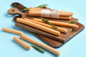 Wooden boards with bunch of tasty Italian Grissini on blue background