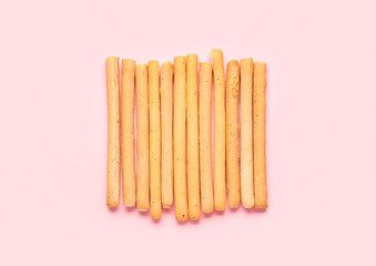 Tasty Italian Grissini on pink background