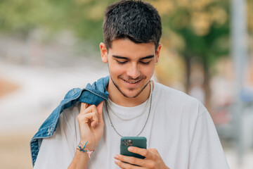 Fototapeta premium young male on the street walking looking at the mobile phone or smartphone