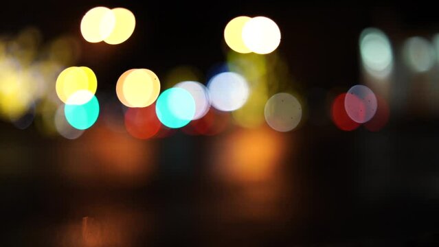 Blurred car lights bokeh in the evening city. Defocused headlights and street lighting at night. Moving bokeh circles of cars at night. Blurred city traffic background