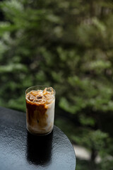 A glass of iced coffee sits on a table in front of a bar.