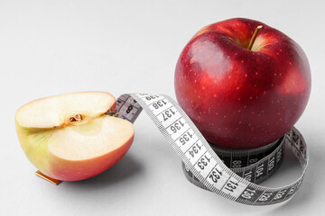 Apple and measuring tape on grey background. Diet concept