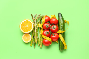 Vegetables, lemon and yellow measuring tape on green background. Diet concept