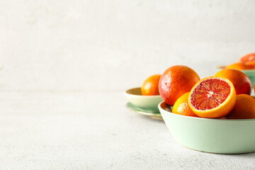 Bowl with tasty blood oranges on light background