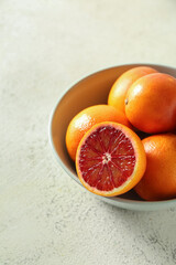 Bowl with tasty blood oranges on light background