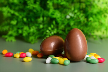 Chocolate Easter eggs and candies on green background