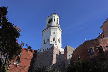 Fototapeta na wymiar Clock tower in Vyborg, Russia. Cityscape with old stone houses in the historic center.