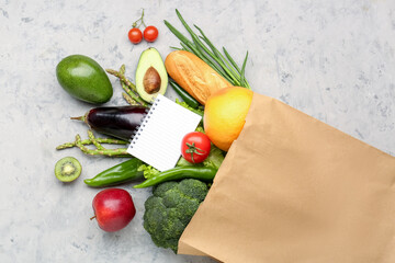 Paper bag with vegetables and blank notebook on grunge background