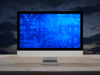 Financial currency symbol on desktop computer monitor screen on wooden table over sunset sky
