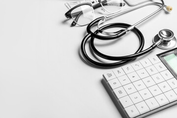 Stethoscope, calculator and glasses on white background