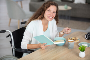 woman in wheelchair at home reading at the table