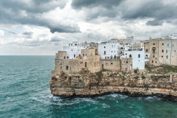 Polignano a Mare, Bari, Italy. Old town built on the rocky cliffs. Traveling concept background with old traditional houses, dramatic cloudy sky and beautiful view of Mediterranean Sea