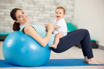 happy young mother with baby with exercise ball having fun