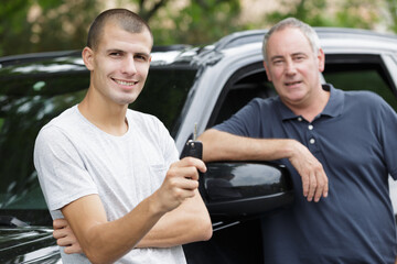 happy young boy holding a key for a car