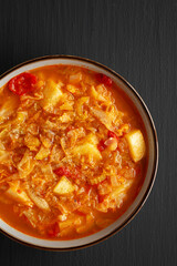 Homemade Shredded Cabbage and Potato Soup in a Bowl on a black background, top view. Overhead, from above, flat lay.