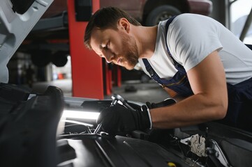 Fototapeta na wymiar Auto mechanic working on car engine in mechanics garage. Repair service.