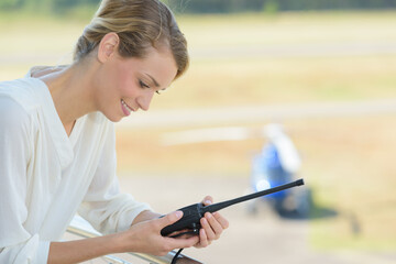 female air traffic control worker in tower using a walkie-talkie