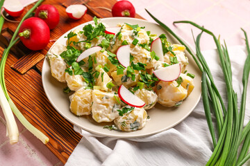 Plate of tasty Potato Salad with greens and radish on table